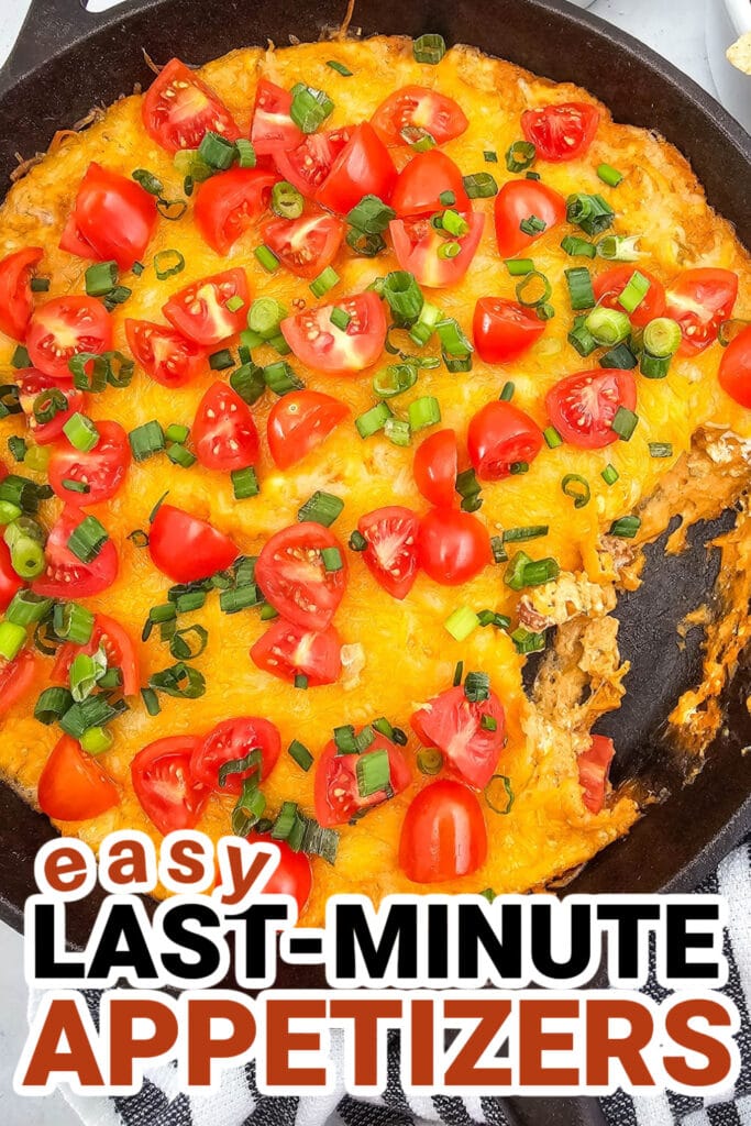 Colorful cheesy appetizer with cherry tomatoes and green onions in a skillet.